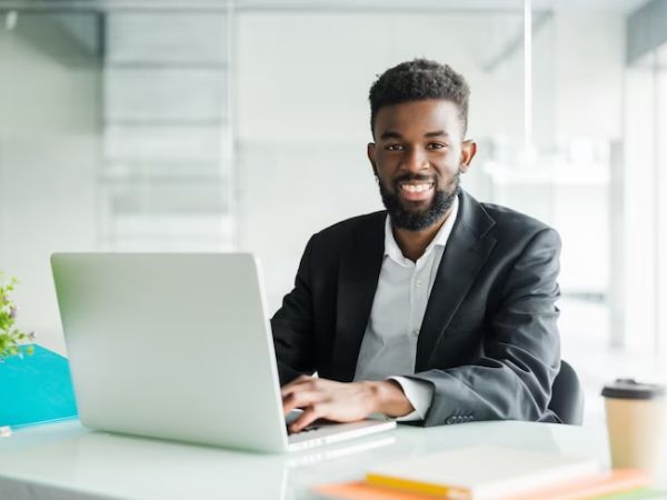 A Nigerian man smiling, conducting a WHOIS search on his computer.